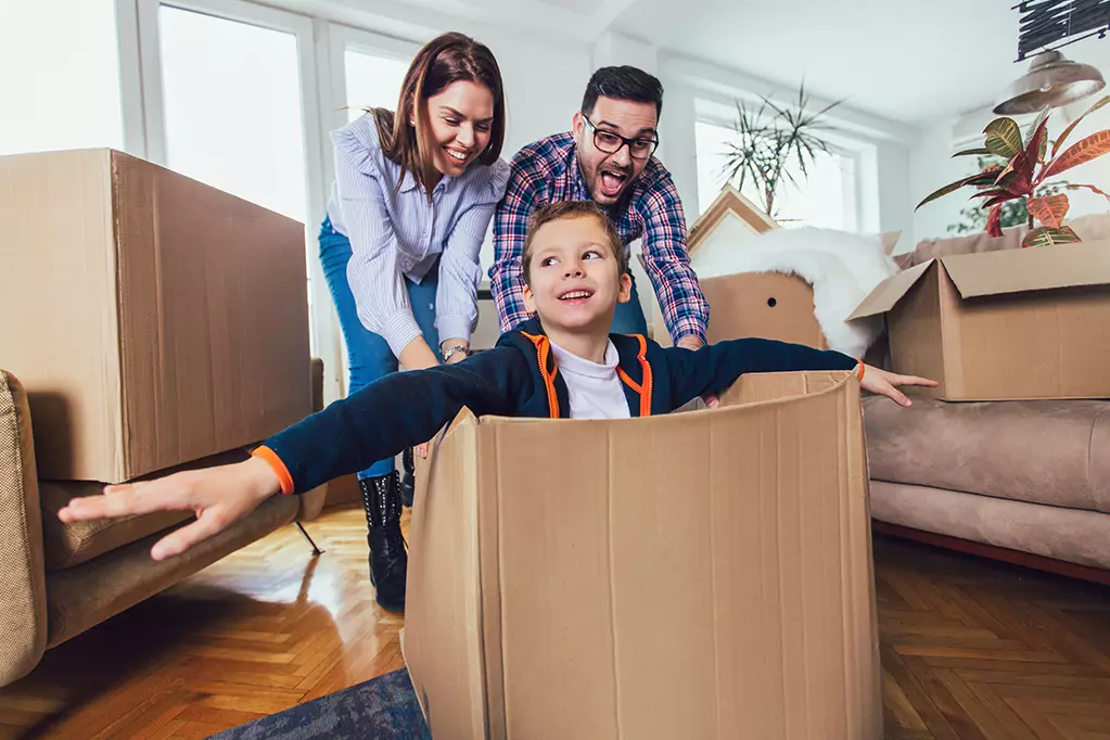 Happy family moving home with boxes around, and having fun